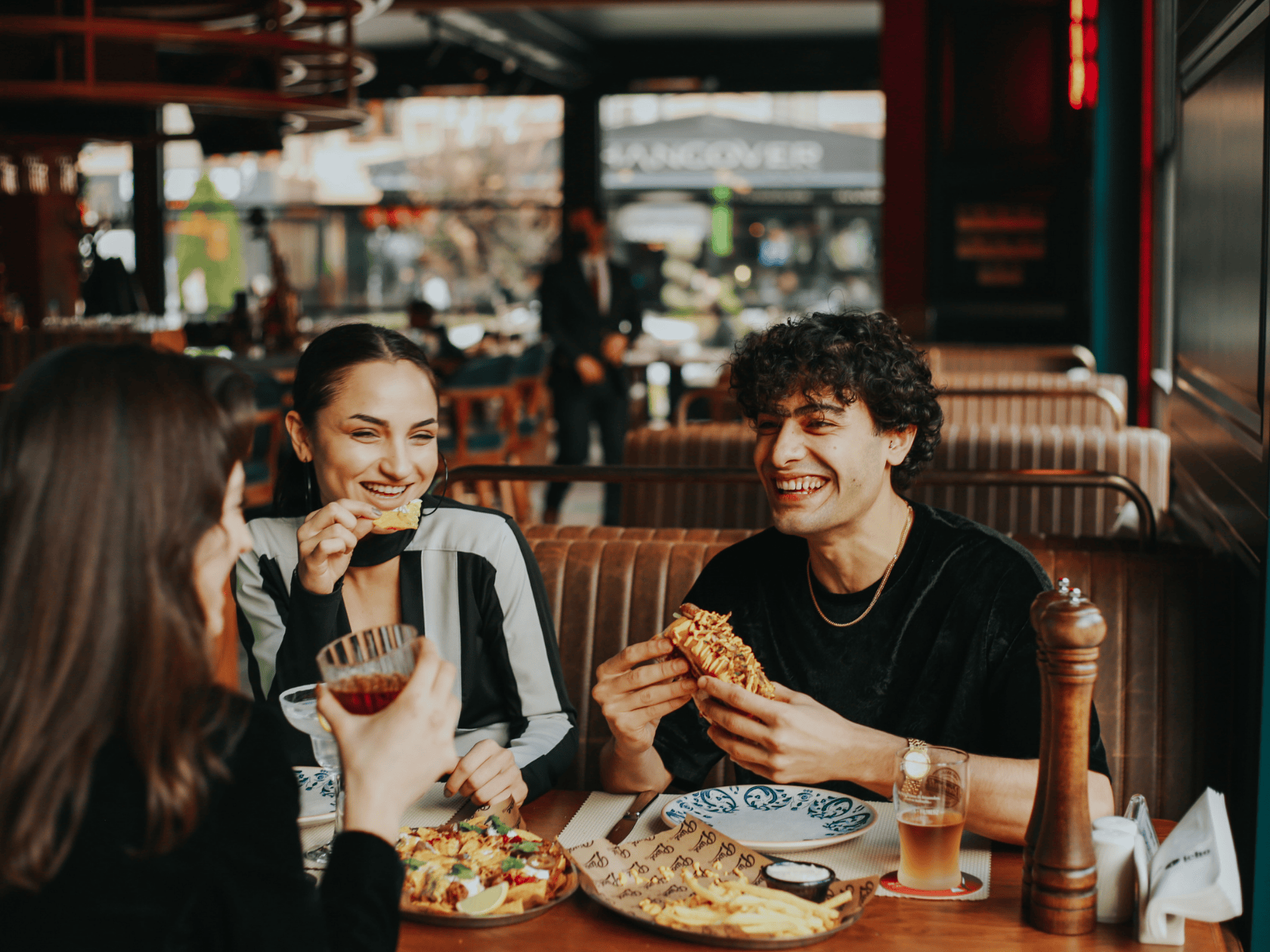 a couple sitting in a booth with a well cooked pizza between them